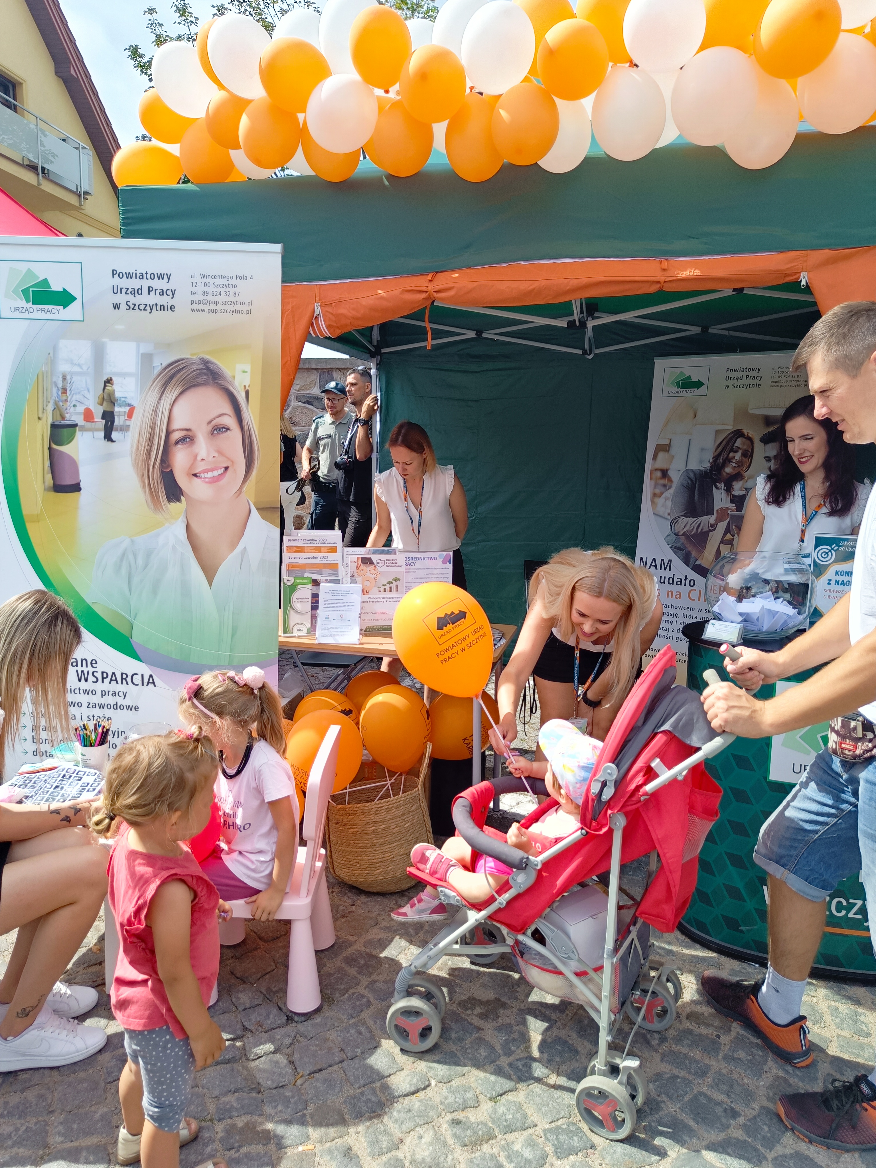 Pracownicy PUP w SZczytnie na tle stoiska reklamowego urzędu pracy