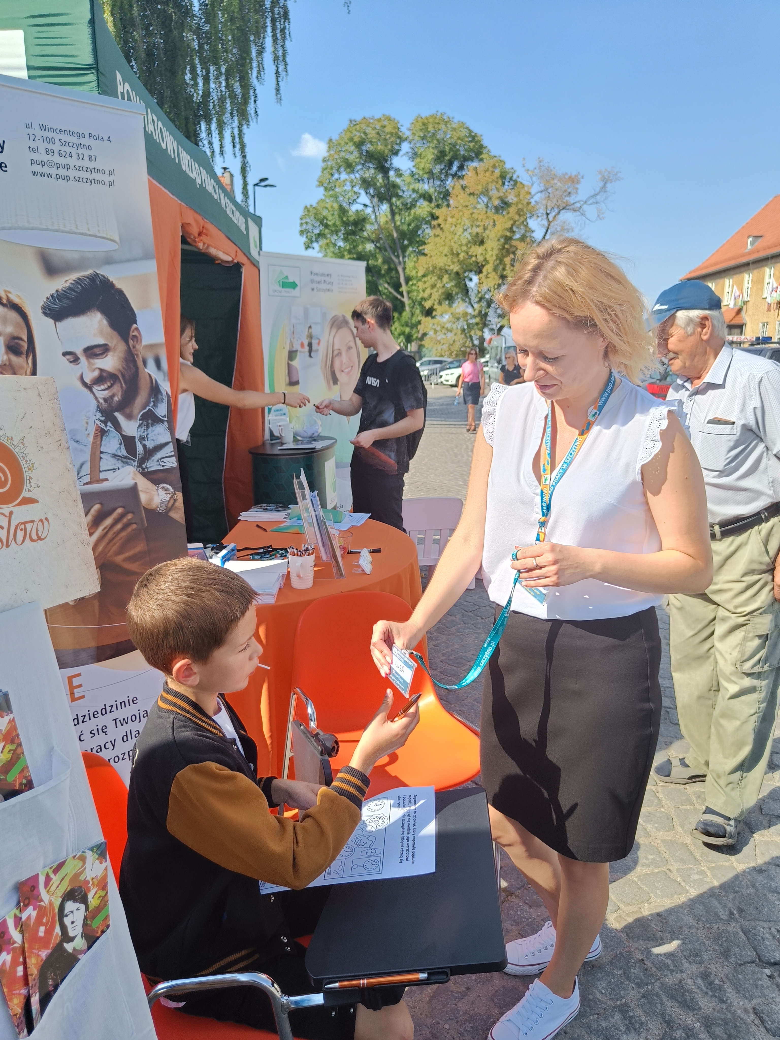 Pracownik PUP Szczytno wręczający plakietkę imienną dla ucznia, który rozwiązał quiz na temat zawodów