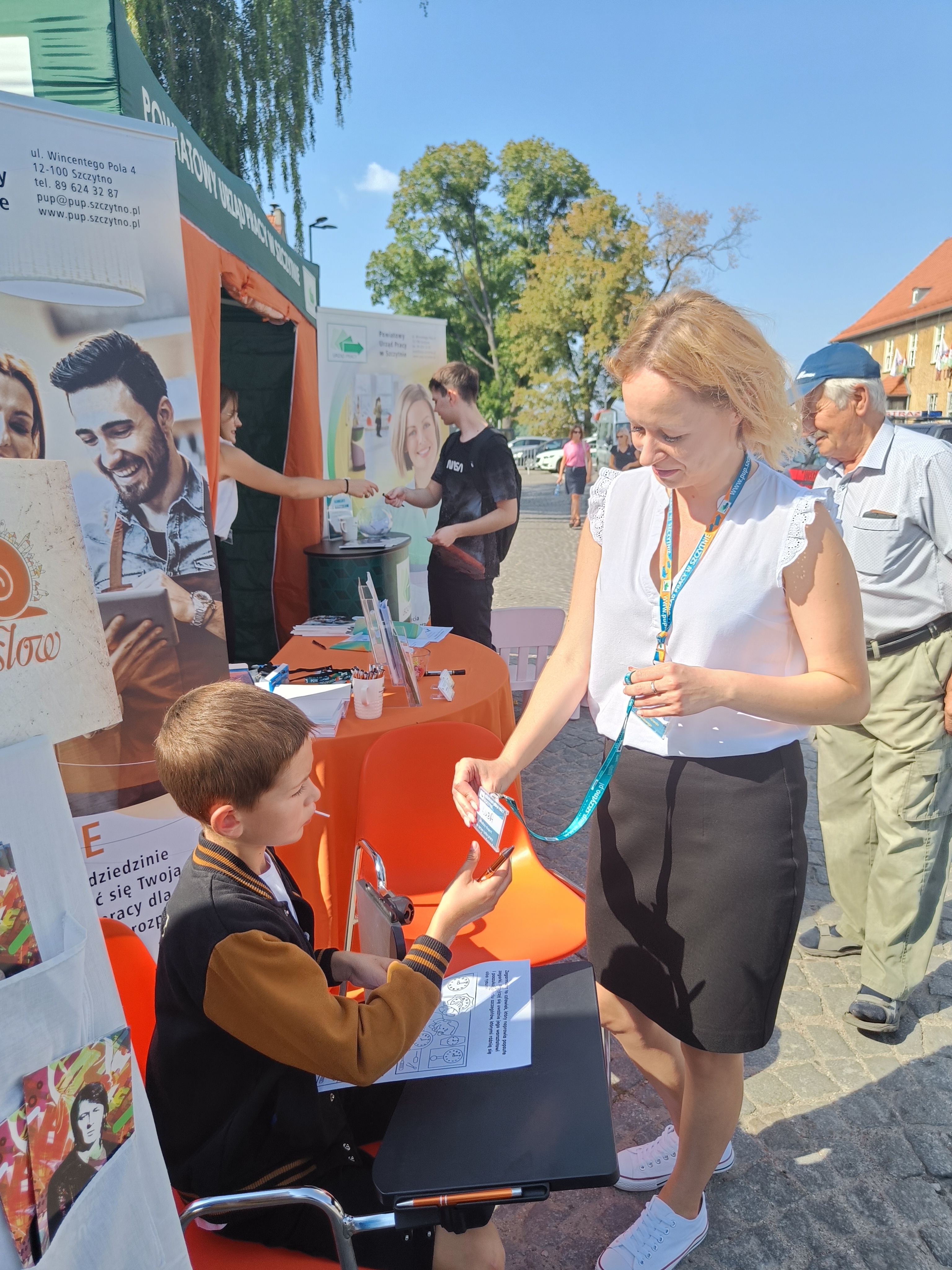 Pracownik PUP Szczytno wręczający plakietkę imienną dla ucznia, który rozwiązał quiz na temat zawodów